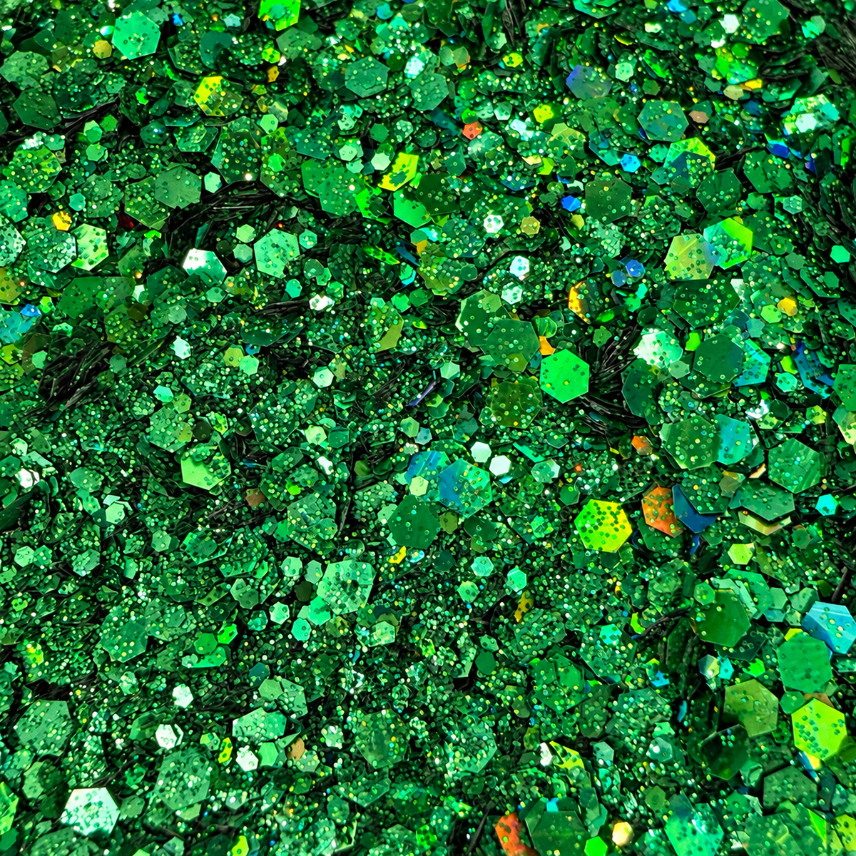 Close-up of Lucky Charm craft glitter showing mixed-size green hexagons and fine particles with rainbow holographic reflections.