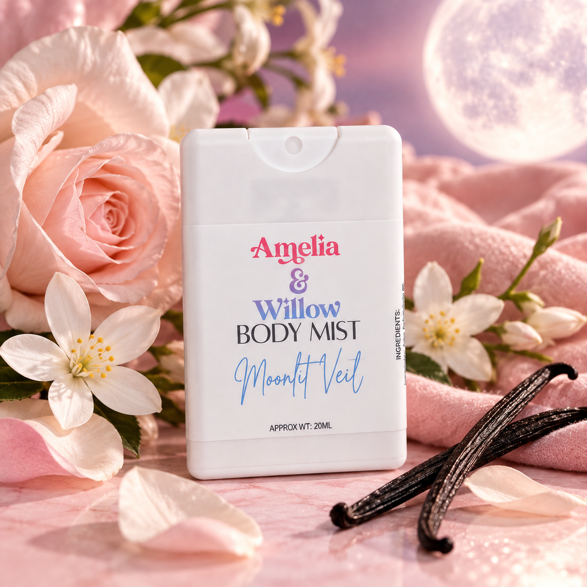 A white rectangular body mist bottle labeled 'Amelia & Willow BODY MIST' and 'Moonlit Veil' is centered on a pink surface with pink roses, white flowers, and vanilla beans. The background is a soft pink and lavender scene with a glowing moon-like orb.