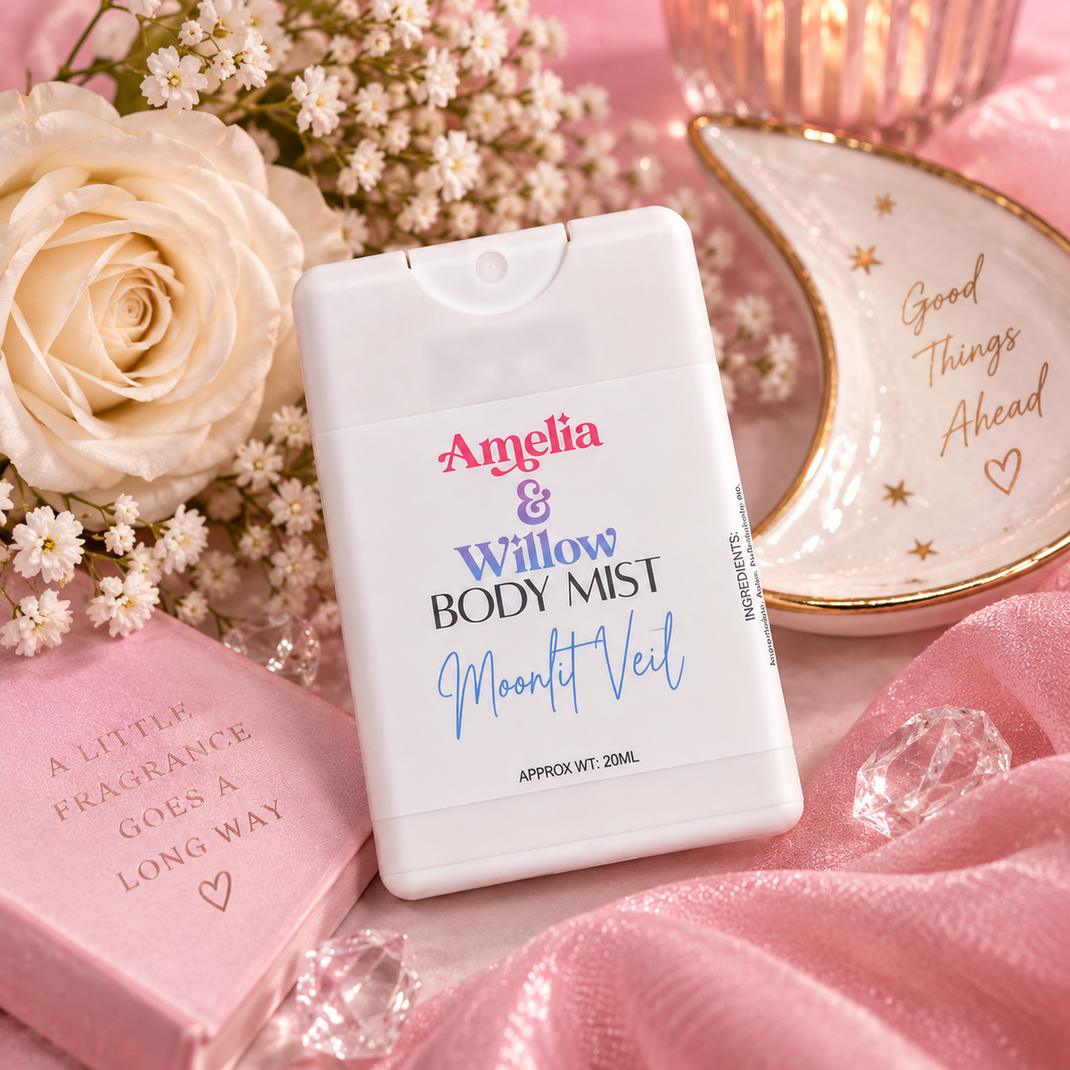 Amelia & Willow Moonlit Veil 20ml body mist styled with white roses, delicate flowers, pink satin and celestial accessories.