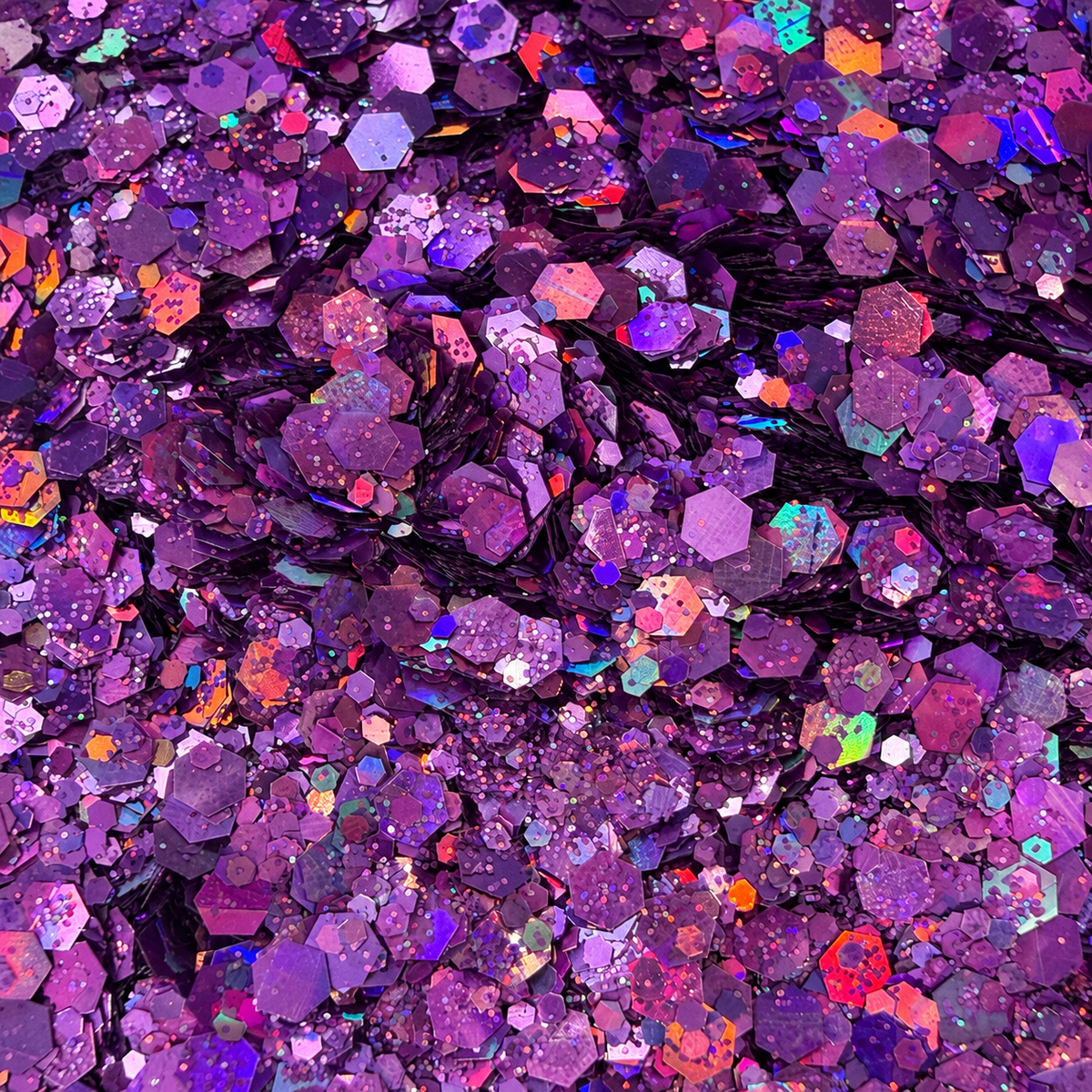 Close-up of Purple Reign craft glitter showing mixed-size purple and lilac hexagons with colourful holographic reflections.