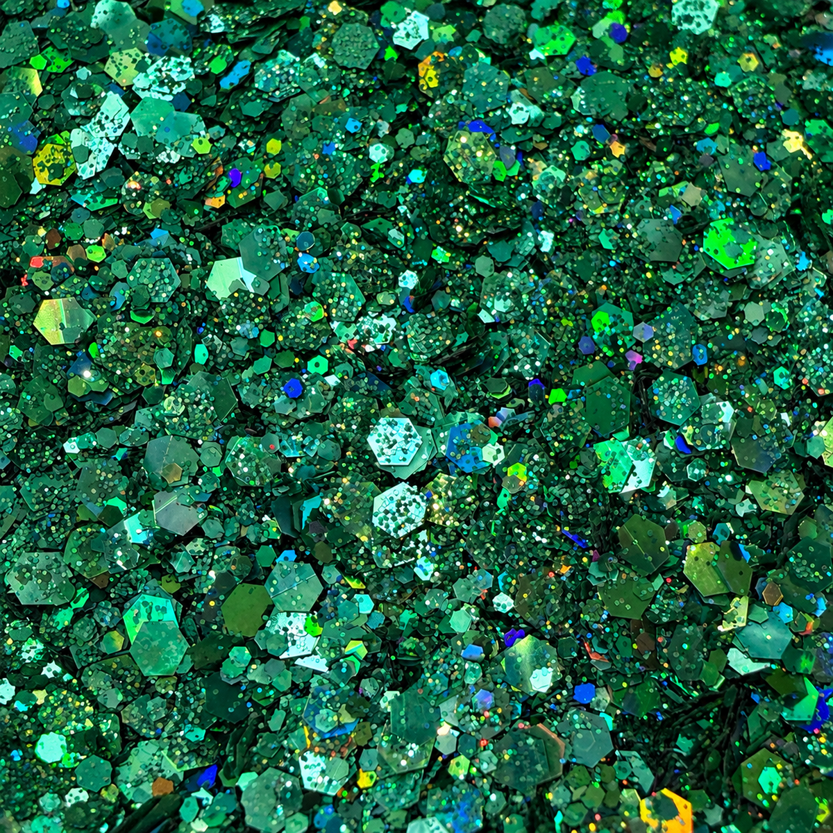Close-up of Jade Jinx craft glitter showing mixed-size deep green and teal hexagons with colourful holographic reflections.