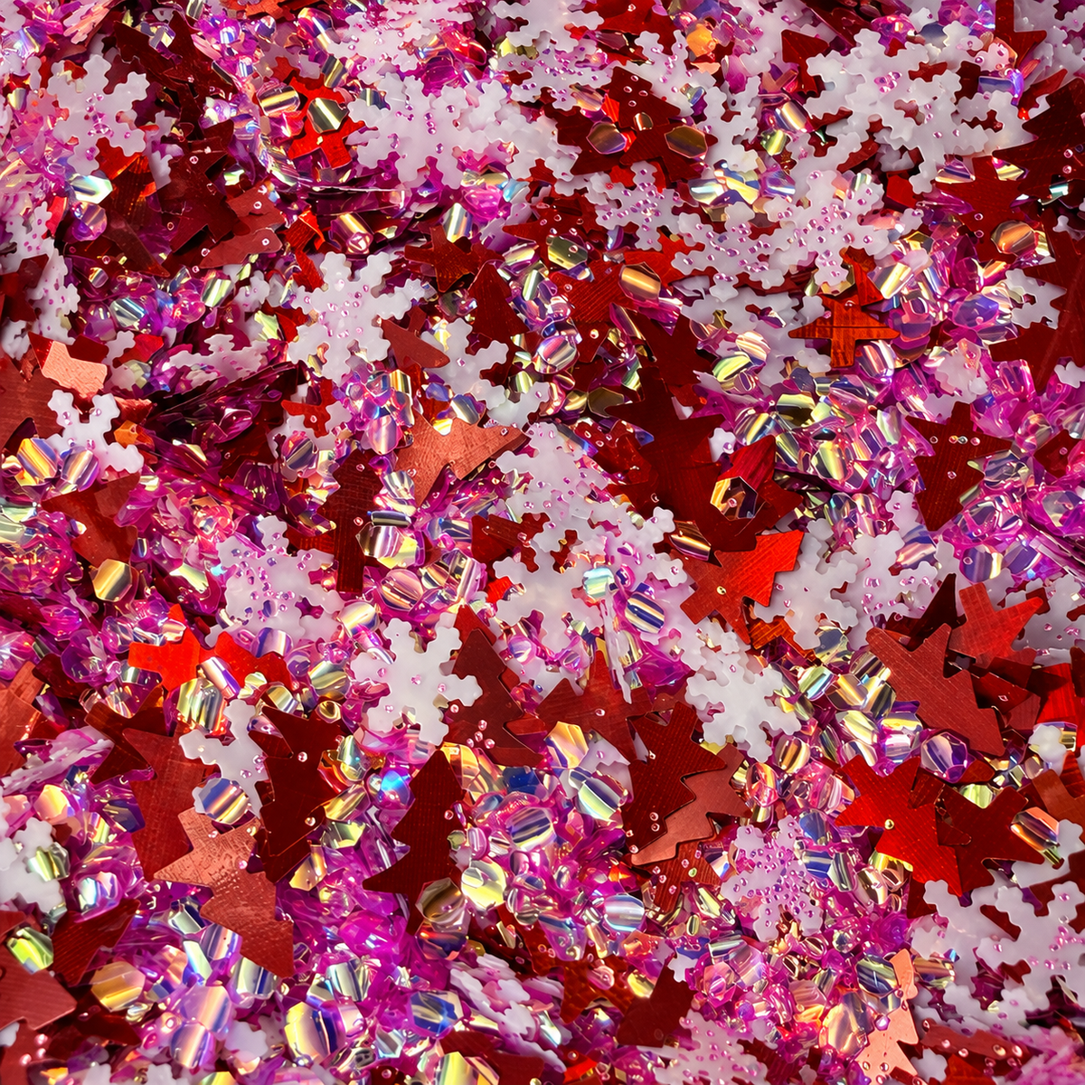 Close-up of Sleigh Belle craft glitter featuring metallic red Christmas trees, white snowflakes and pink iridescent pieces.