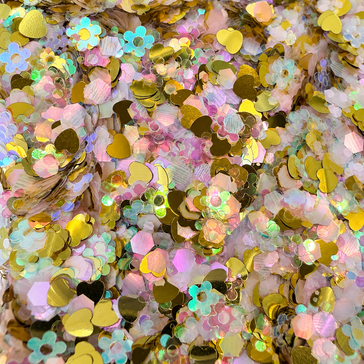 Close-up of Golden Hour Blooms craft glitter with metallic gold hearts, pastel flowers and pearly iridescent hexagons.
