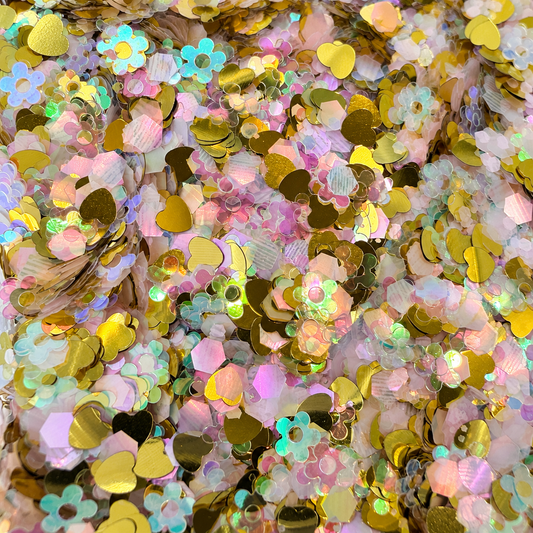 Close-up of Golden Hour Blooms craft glitter with metallic gold hearts, pastel flowers and pearly iridescent hexagons.