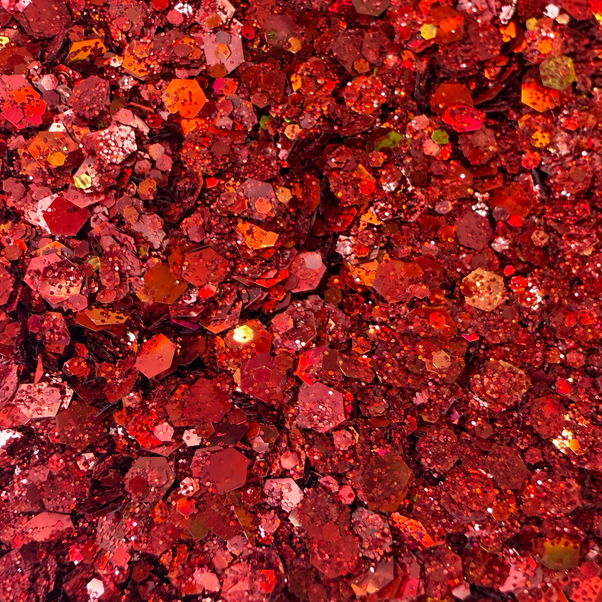 Close-up of Scarlet Fever craft glitter showing mixed-size ruby-red metallic hexagons and fine sparkling particles.