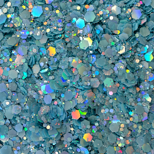 Close-up of Blue Reverie craft glitter showing powder-blue and aqua hexagons in mixed sizes with iridescent reflections.