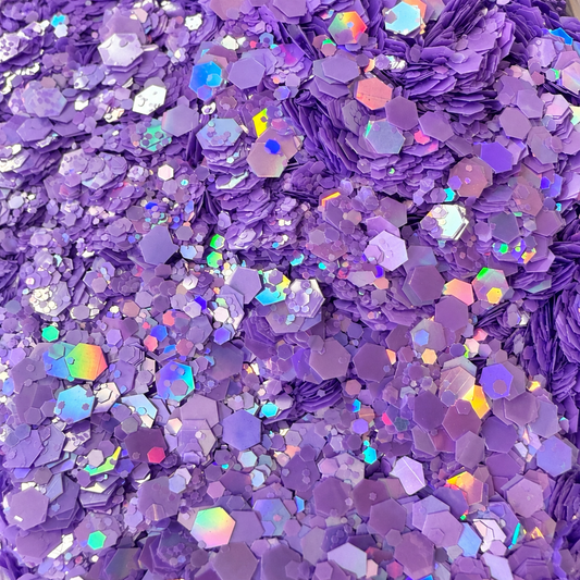 Close-up of Lilac Daydream craft glitter showing mixed-size lilac and lavender hexagons with colourful iridescent reflections.