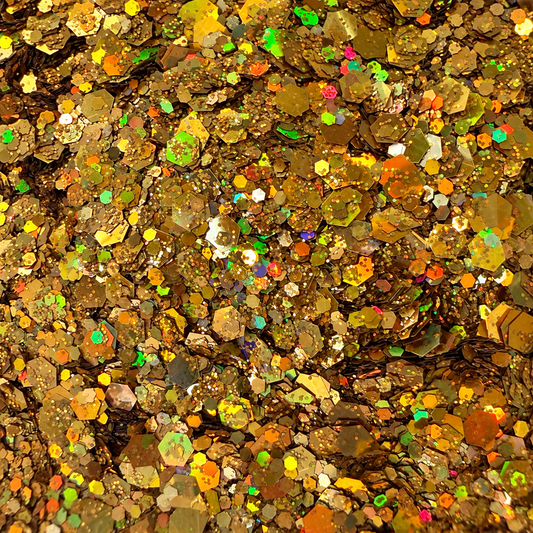 Close-up of Gilded Glow craft glitter showing mixed-size metallic gold hexagons and fine particles with rainbow holographic reflections.