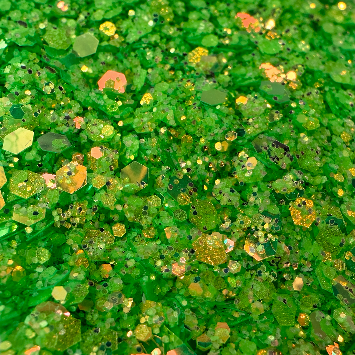 Close-up of Poison Ivy craft glitter showing mixed-size green hexagons with golden and peach iridescent reflections.